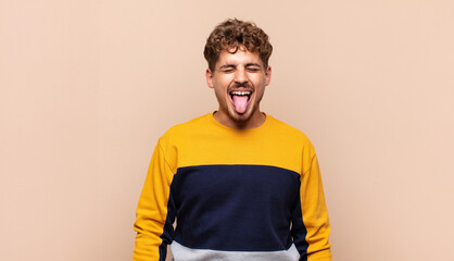 young man with cheerful, carefree, rebellious attitude, joking and sticking tongue out, having fun