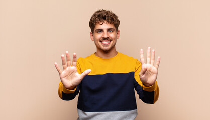 young man smiling and looking friendly, showing number nine or ninth with hand forward, counting...