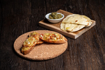 Bruschetta with half dried tomatoes and cheese. Middle Eastern meze with pita, olives, colorful hummus, babaganush, pickles, vegetables. Healthy food, vegan vegetable dish. tacos and snack wood table