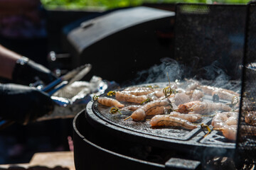 A professional cook prepares shrimps on the grill outdoor, food or catering concept