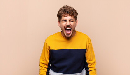 young man shouting aggressively, looking very angry, frustrated, outraged or annoyed, screaming no