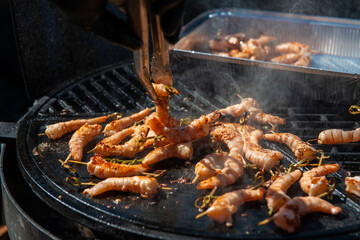 A professional cook prepares shrimps on the grill outdoor, food or catering concept