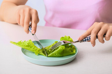 Woman eating salad at table, closeup. Concept of anorexia