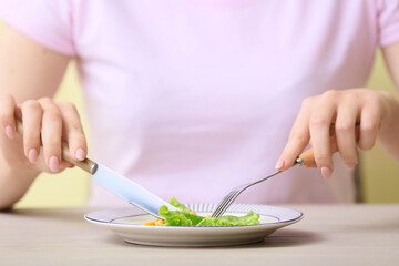 Obraz na płótnie Canvas Woman eating vegetables at table, closeup. Concept of anorexia
