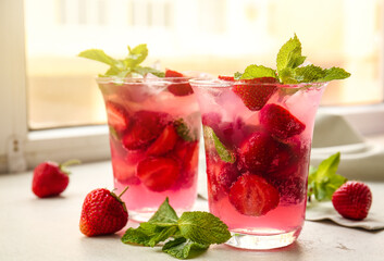 Glasses of fresh strawberry mojito on window sill
