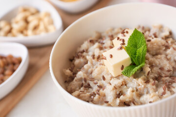 Bowl with tasty sweet oatmeal on table, closeup