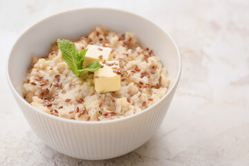 Bowl with tasty sweet oatmeal on light background
