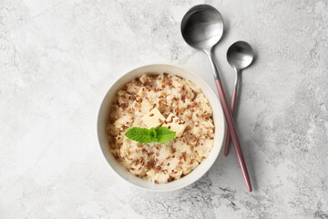 Bowl with tasty sweet oatmeal on light background