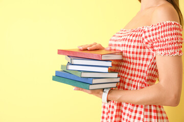 Beautiful young woman with books on color background