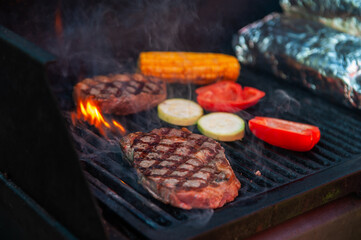 Beef steaks with vegetables on the grill with flames