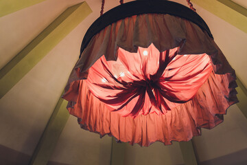 Red homemade lampshade with a fringe of fabric on the background of the illuminated canopy.