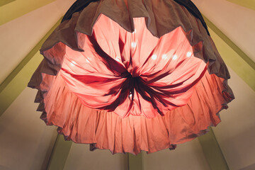 Red homemade lampshade with a fringe of fabric on the background of the illuminated canopy.