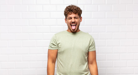young man with cheerful, carefree, rebellious attitude, joking and sticking tongue out, having fun