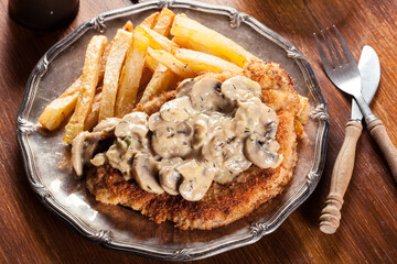 Traditional hunter schnitzel with a mushroom gravy and french fries