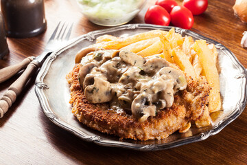 Traditional hunter schnitzel with a mushroom gravy and french fries