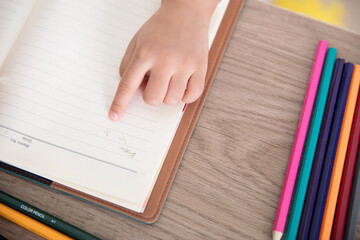 The child's little finger is pointing at the drawing on the notebook