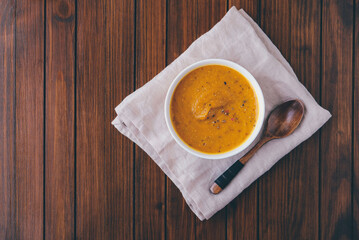 Hot spicy pumpkin soup in a bowl on wooden rustic background.