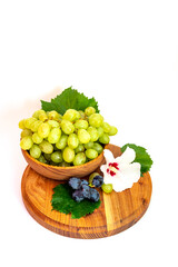 Bunches of grapes and hibiscus flower on a wooden board. White background.
