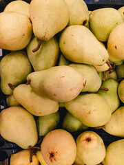 Fresh, ripe, yellow Pears (Latin Pyrus) are on top of each other in the supermarket for sale. Vertical photo background.
