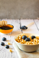 Honey rings with blueberries in a bowl on the table wooden background. Copy space. Flat lay. Horizontal orientation.