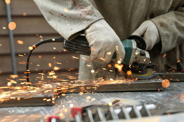 worker's hands sawing with a grinder close-up