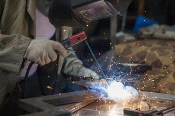 worker welds metal with electric welding