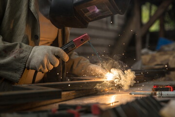 worker welds metal with electric welding