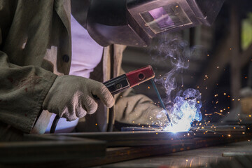 worker welds metal with electric welding