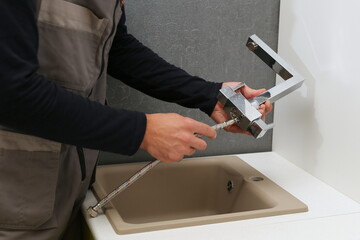 plumber installs kitchen faucet. refurbishment in the kitchen 