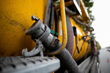 Side view of powerful professional modern yellow sewage sewerage truck working near a house pumping basement canalisation water