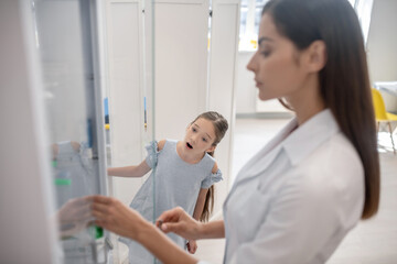 Fototapeta premium Girl watching a doctor opening the vitrine with pills