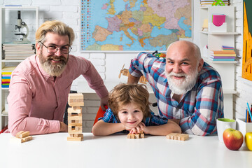 Three generations of active men playing in living room. Jenga game at home.