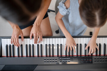 Girl and her teacher playing piano together