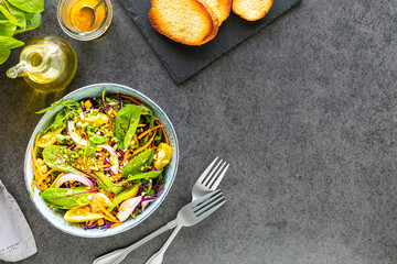 Fresh vegetable and fruit salad in a plate on a black stone background. Top view
