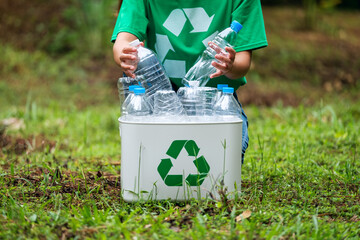 A woman collecting and putting plastic bottles into a recycle bin in the outdoors