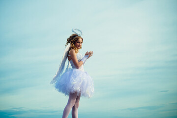 Charming curly little girl in white dress and wings - angel cupid girl. Enjoying magic moment....