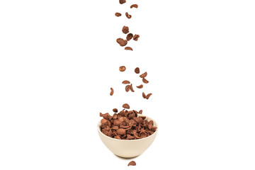 Chocolate corn flakes falling to the white bowl isolated on white. Motion.