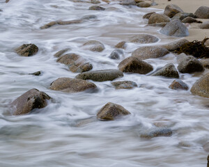 Long exposure Pacific seascape waves on the rocky stoney shore. Slow shutter speed used to see the movement (Soft focus shot)