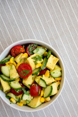 Fresh Avocado Tomato Salad in a bowl, top view. Flat lay, overhead, from above. Copy space.