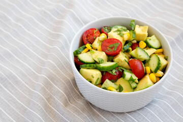 Fototapeta na wymiar Fresh Avocado Tomato Salad in a bowl, low angle view. Copy space.