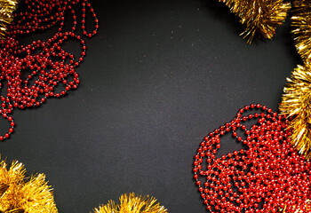 Christmas golden tinsel and red garland on black background. Happy New Year Banner, Merry Christmas. Xmas posters, greeting cards, headers, website, sale banner. Winter time. Top view.