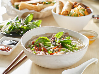 vietnamamese meal with beef pho bo soup accompanied by hoisin sauce and sriracha