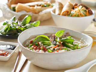 vietnamamese meal with beef pho bo soup accompanied by hoisin sauce and sriracha
