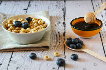 Honey rings with blueberries in a bowl on the table wooden background. Copy space. Flat lay. Horizontal orientation.
