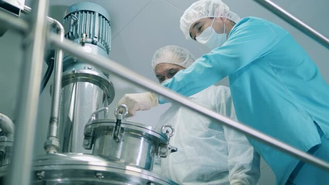 Men in medical coats work with machine in laboratory.