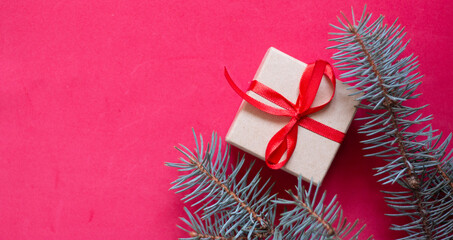 Christmas gift from a round box, tied with a red ribbon on a red background with wooden cones. The view from the top. Space for text. A soft picture
