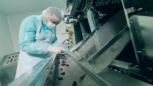 Male pharmacist checks dark capsules in laboratory. Pharmaceuticals production line at a modern pharmaceutical facility.