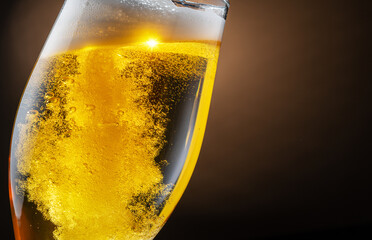 Jet of beer is poured into a beer glass, causing a lot of bubbles and foam.