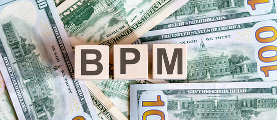 Concept words BPM on wooden blocks on a beautiful background from dollar bills.