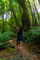 A very happy young woman trekking, on the trail next to ferns, in the Cubo de la Galga natural park on the northeast coast on the island of La Palma, Canary Islands. Spain